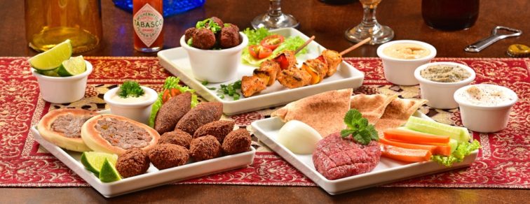 mesa com vários pratos árabes e cerveja